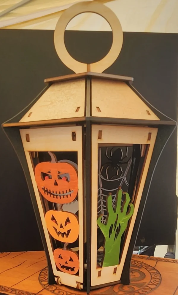 A wooden lantern with halloween decorations on it.