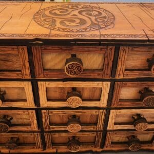 A wooden chest of drawers with some design on it